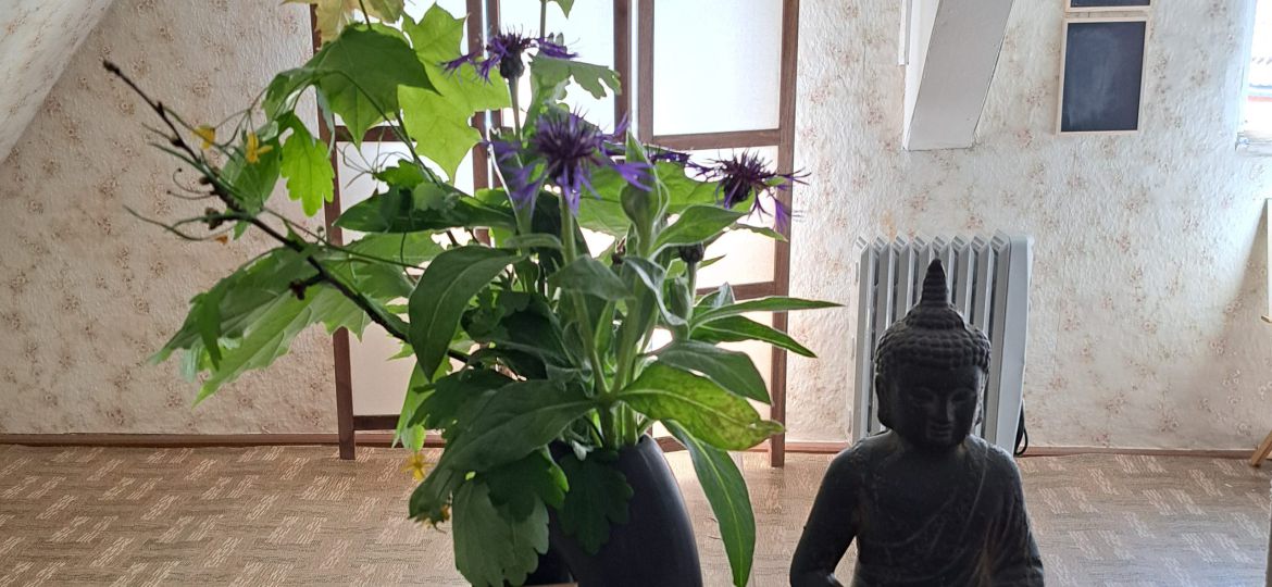 Buddhastatue mit Blumen auf einem Altar in einem Zimmer.