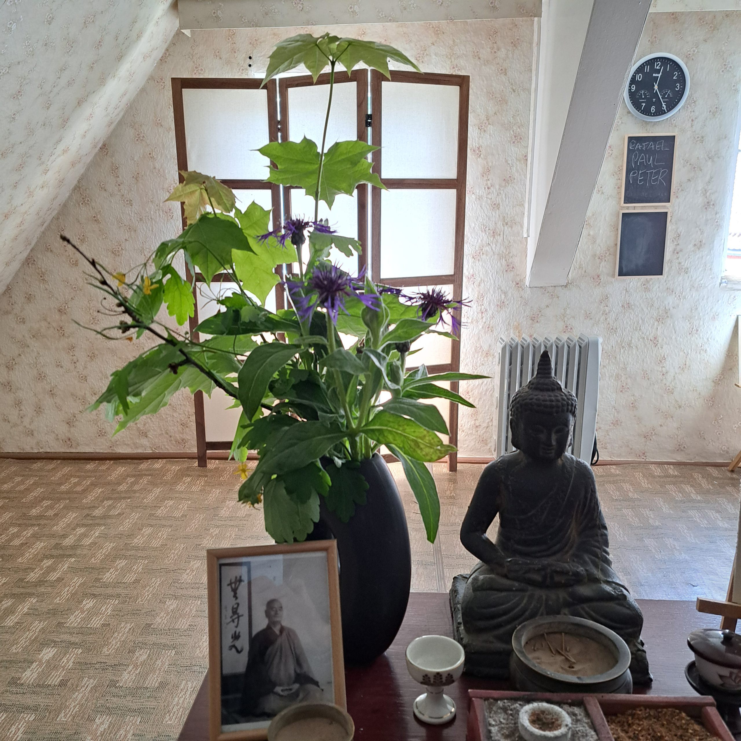 Buddhastatue mit Blumen auf einem Altar in einem Zimmer.