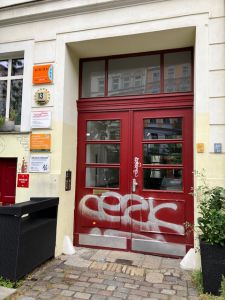 Hauseingang Oderstraße 13 rote Haustür mit bunten Schildern an der Wand