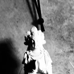 Statue mit gefalteten Händen vor einer Uhr mit Zeigern.